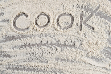 Grey cooking background of spilled wheat flour on stone background with text cook