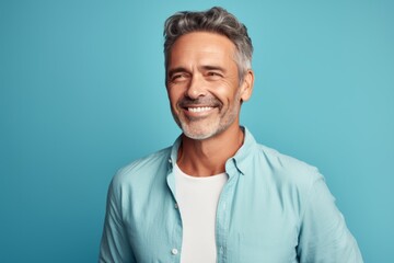 Obraz premium Portrait of a blissful man in his 50s wearing a simple cotton shirt isolated in pastel teal background