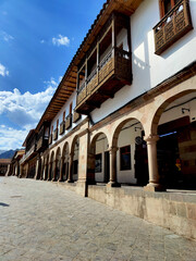 Fachada colonial con balcones de madera y arcos en una plaza histórica del pueblo de Cuzco, Perú.