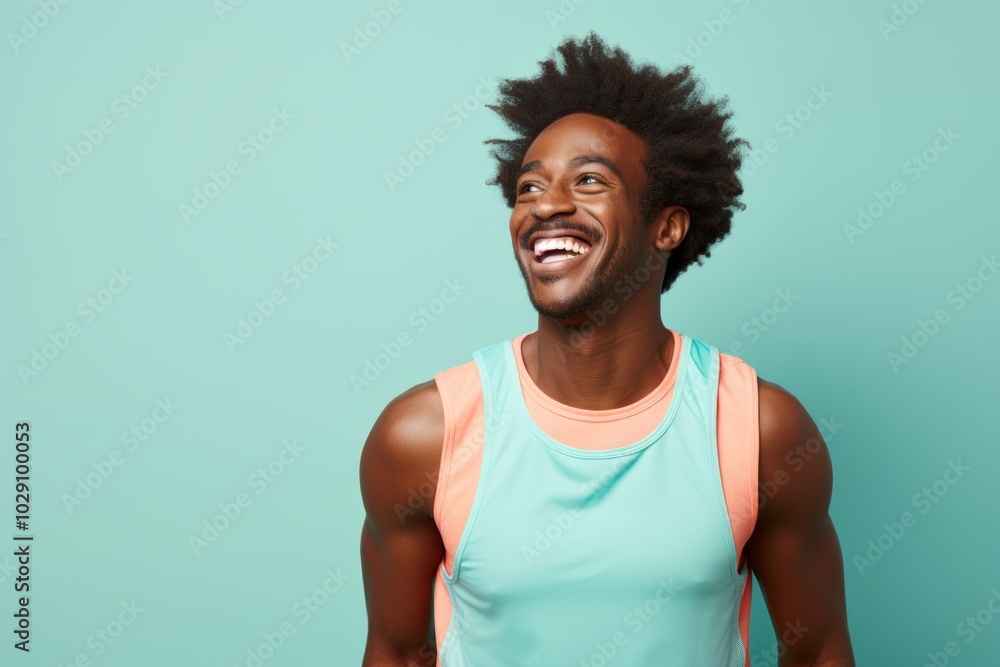 Canvas Prints Portrait of a joyful man in his 20s wearing a lightweight running vest while standing against pastel teal background