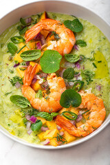 Green avocado gazpacho with shrimp and herbs, basil, lime, peaches, nasturtium leaves and purple onions. Spring and summer cuisine, healthy recipes full of proteins, fats and vitamins. Fresh seafood