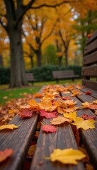Autumn park bench with fallen leaves in warm golden hues against blurred background