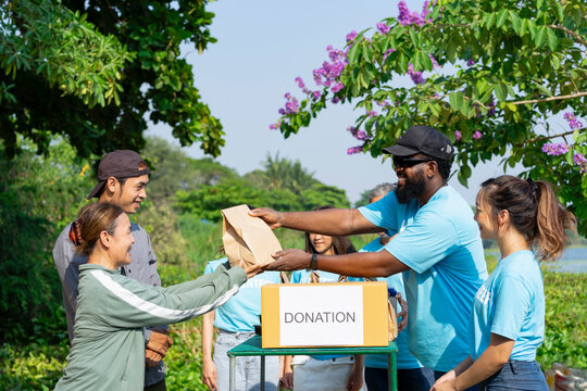 volunteers giving paper bag of food to asian senior woman and son,group of volunteers helping the needy to distribute of food items and water in the rural park