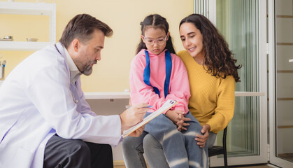 Obraz premium Doctor man care caucasian sitting use stethoscope check girl sick illness daughter who came to hospital with mother woman three people with talk helping support give advice inside treatment room