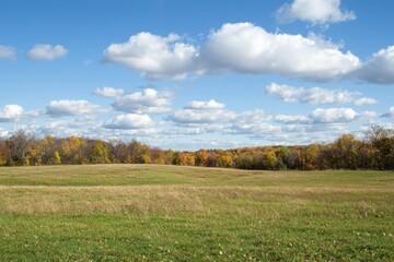 Obraz premium Autumn landscape featuring vibrant colors and a vast sky with fluffy clouds in the afternoon