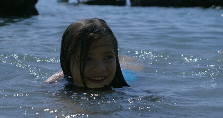 Smiling girl swimming in lake, captured in slow-motion at 800 fps, enjoying summer day, playful and...