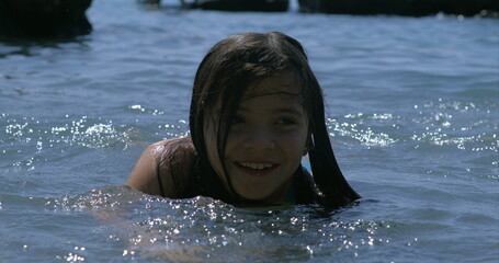 Smiling girl swimming in lake, captured in slow-motion at 800 fps, enjoying summer day, playful and...