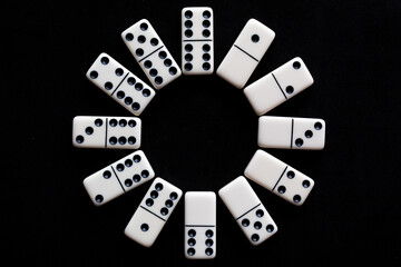 Domino tiles in circle on black background.