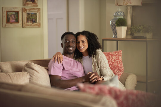 Smiling young multiracial couple sitting on their living room sofa