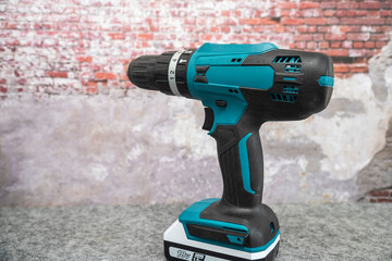 electric turquoise power drill against a brick wall