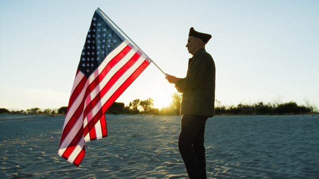 Old Veteran walking in the beach alt sunset with Usa Flag 