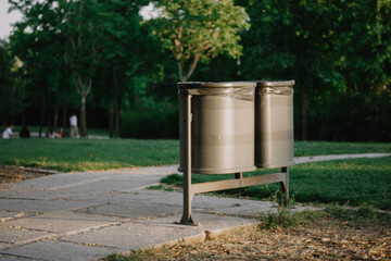 Plastic trash can. Metal black garbage cans in a city park in summer day. Care for the environment,...