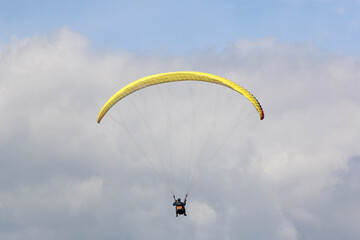 Tandem Paraglider flying in a cloudy sky	