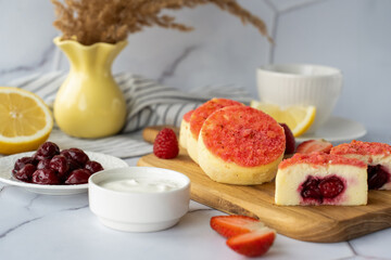 Delicious cheesecake with cherry filling and fresh berries served with sour cream and coffee in a...