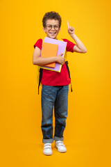 Vertical full length studio portrait of  happy smiling african american schoolboy posing with a...