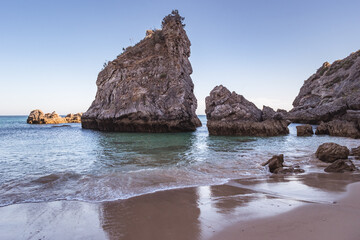 Rocks in the sea water and wave on the sand at evening on Ribeiro do Cavalo beach, Sesimbra PORTUGAL
