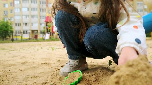 Little child girl playing with toys in the sandbox at spring