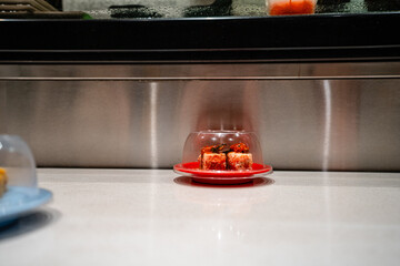 various types of sushi on conveyor belt in a Japanese restaurant. Shushi Go Round is a famous form of fast food in Asia, also known as sushi train.