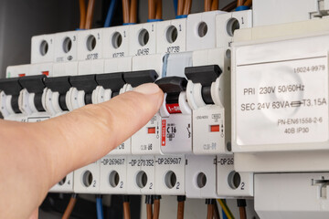 Hand Turning Off Circuit Breaker in Electrical Panel