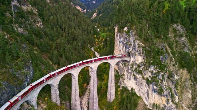 Landscape of Switzerland: Aerial view of red train passing the Landwasser viaduct in Swiss Alps