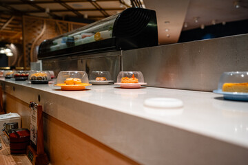 various types of sushi on conveyor belt in a Japanese restaurant. Shushi Go Round is a famous form of fast food in Asia, also known as sushi train.