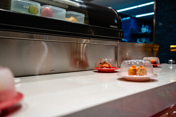 various types of sushi on conveyor belt in a Japanese restaurant. Shushi Go Round is a famous form of fast food in Asia, also known as sushi train.