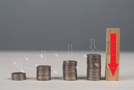 Coins in declining stacks with percentage signs and arrows symbolize financial decline