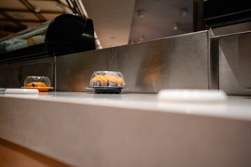 various types of sushi on conveyor belt in a Japanese restaurant. Shushi Go Round is a famous form...