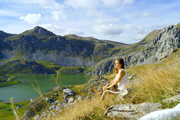 Outdoor recreation in beautiful places of Montenegro: woman meditating in the mountains. Portrait of a tourist sitting on a mountainside near Lake Kapetanovo, enjoying the fresh air and autumn sun