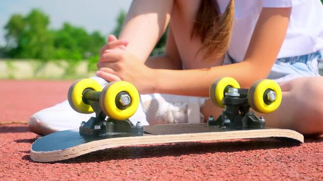 Kid girl hurting knee skateboarding outdoor, girl crying holding leg after falling down from longboard. Accident with skateboard, urban extreme activity