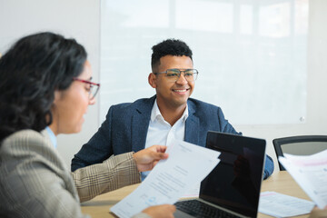 Young latin colleagues, man and woman, working on a collaborative business project in co-working office