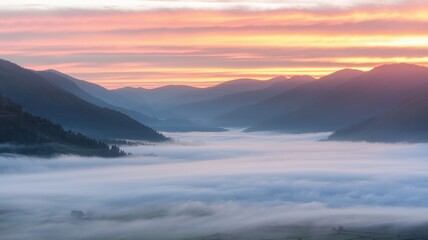 Stunning landscape with mountains and a foggy valley under a colorful sunrise.