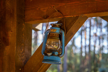 an old kerosene lamp hanging on wooden beams next to the house