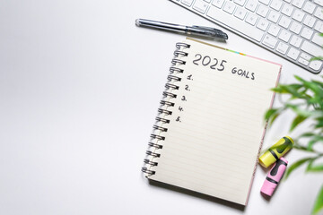 Notebook with goals for 2025 on white background. Top view. Working atmosphere. Year planning and...