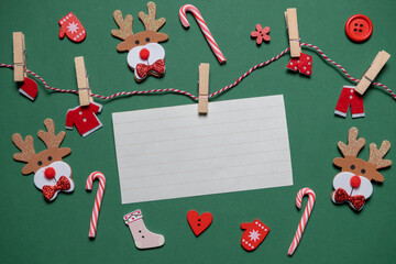 Sheet for text. New Year decor (Christmas trees, reindeer, socks, lollipops) on green background. Top view. Backgrounds and presentations