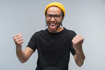 Studio portrait of joyful euphoric happy smiling stylish african american young man celebrating...