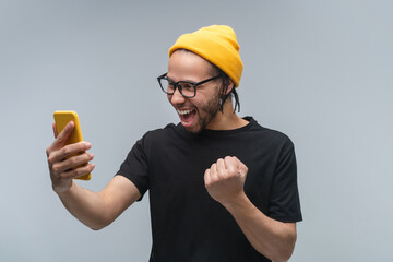 Studio shot of stylish euphoric young African American man in trendy spectacles, basic black...