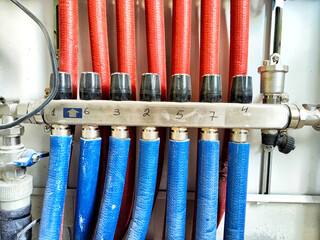 Colored fluid distribution manifold showing numbered red and blue hoses connected in a mechanical...