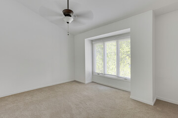 Empty Carpeted Room With Large Window And Ceiling Fan.