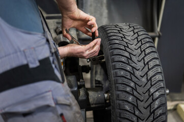 Mechanic removes wheel balance weight from car wheel. 