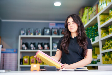 beautiful latin american saleswoman entrepreneur at the counter holding air filter in an auto parts supply store	