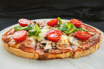 A side view of a Capricciosa-style bruschetta topped with tomatoes, mozzarella, and basil. The toasted bread provides a crunchy base for the fresh ingredients.