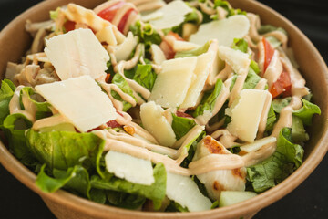 A close-up of a vibrant chicken salad featuring grilled chicken strips, fresh vegetables, and leafy greens, lightly dressed with vinaigrette.