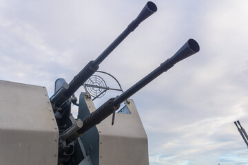 Double-barreled naval automatic cannon against the sky close-up, military background