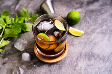 Cold Cuba Libre or Long island iced tea cocktail with brown rum, cola, mint, lime, muddler, jigger and glass