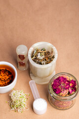 Homeopathy. Homeopathic medicines, small pills, herbs in a glass jar on a kraft background. Alternative medicine.