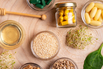 Homeopathy. Homeopathic medicine, pills and capsules in a beautiful composition with green leaves and various plants on a wooden desk on an orange background, top view