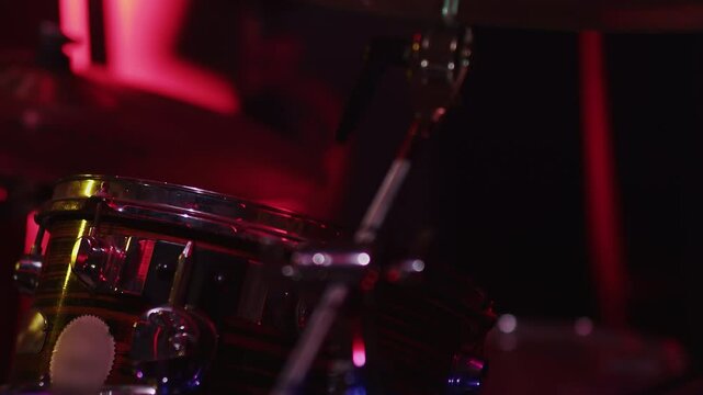 Musician playing snare drum on stage with dramatic lighting