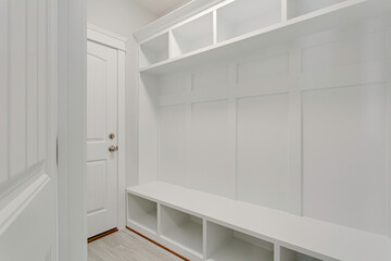 White Mudroom With Built-In Storage Benches And Hooks.