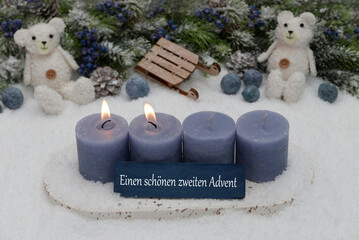 Zweiter Advent: Dekoration mit vier blauen Adventskerzen, Weihnachtskugeln und Tedybär im Schnee.